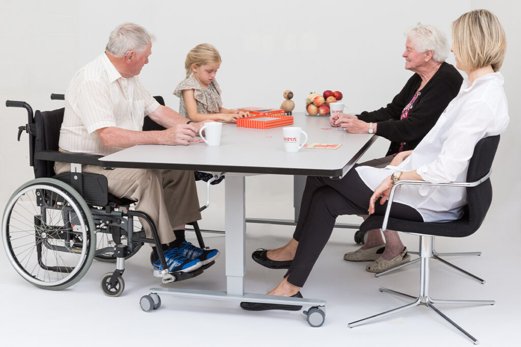 Wheelchair user and family members of different ages seated together at a Ropox accessible group table